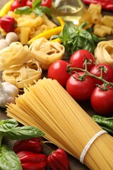 Different types of raw pasta and products on table, closeup