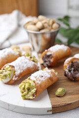 Delicious cannoli with ricotta cheese, pistachios and powdered sugar on light grey table indoors, closeup