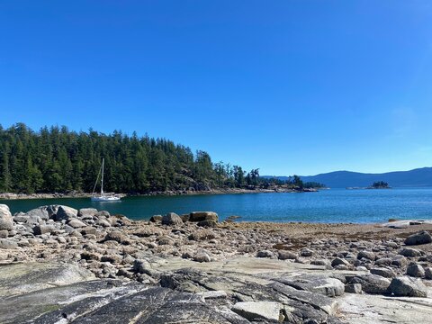 Calm turquoise water and rocky shoreline at Hardy Island on the British Columbia coast, framed by forested islets and clear summer skies.