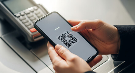 Close-up of a person using a smartphone to scan a QR code for a contactless payment at a point of sale terminal.
