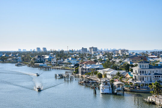Boats cruising by waterfront homes in Fort Myers Beach on Estero Island, southwest Florida in Lee County