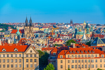 Fototapeta premium Towers above the old town of Prague behind leaves, Czech republi