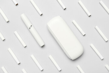 Modern electronic cigar and many sticks on grey background