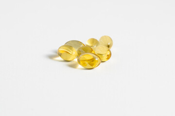 golden softgel capsules on white background, vitamins or omega 3 supplements