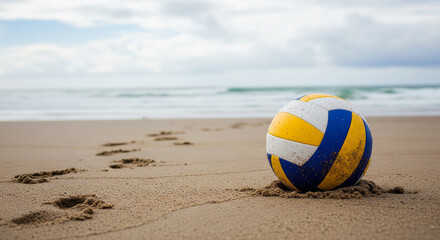 Volleyball on sandy beach with ocean and cloudy sky