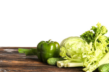 Fresh vegetables on brown wooden kitchen table against white background