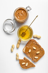 Toasts with peanut butter, nuts and bowl of honey on white background
