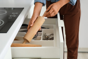Woman putting rolling pin into kitchen drawer