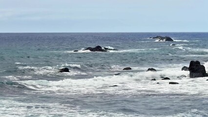Naklejka premium The beautiful ocean waves lap against the rocky shoreline, creating a serene atmosphere