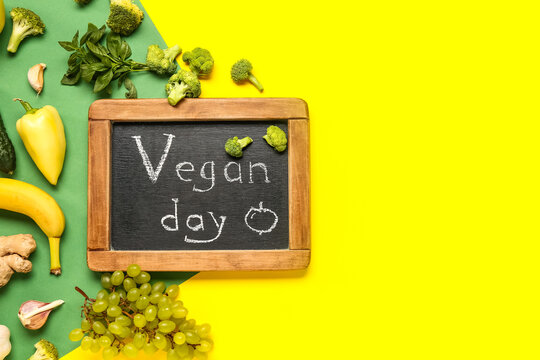 Chalkboard with word VEGAN DAY, fresh vegetables and fruits on color background
