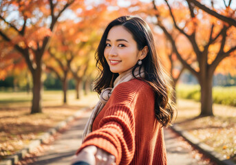 手を引いてデートする茶色のニットとストールを着た女性