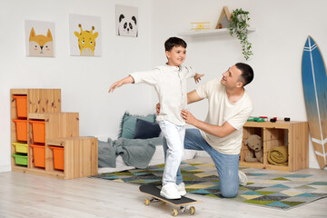 Cute little boy with his father skating in bedroom
