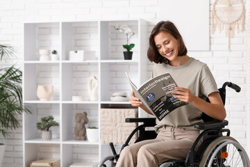 Young pretty woman in wheelchair reading magazine at home
