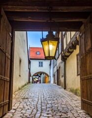 Cobblestone alleyway, vintage lamp, wooden archway