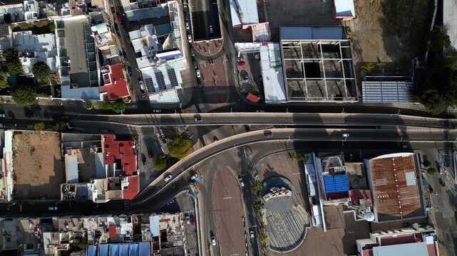 Aerial view of vehicles traveling on an avenue and overpass in Mexico. In downtown Aguascalientes. From a top-down angle.