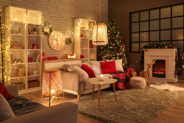 Interior of stylish living room with comfortable sofas, shelving unit and fireplace decorated for Christmas celebration at evening
