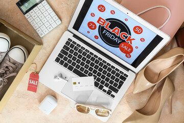 Laptop with Black Friday sale advertisement, credit card and female accessories on grunge background
