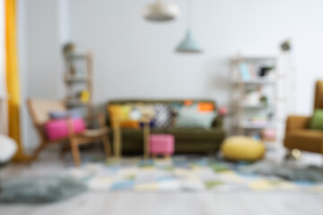 Blurred view of stylish living room with sofa, armchair and shelf units