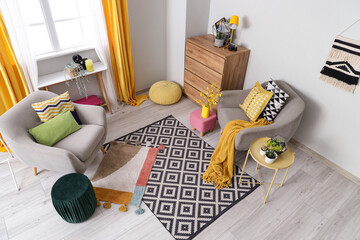 Interior of stylish living room with grey armchairs, table and poufs