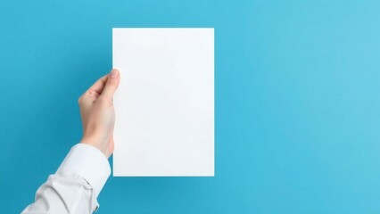 Hand holding a blank white brochure or flyer against a bright blue background