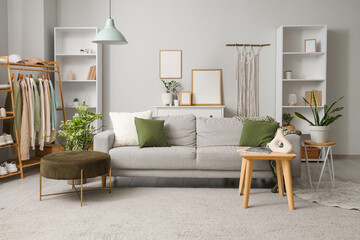 Interior of living room with clothes rack, sofa and shelf units