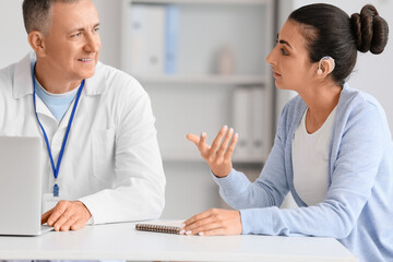Young woman with hearing aid visiting otolaryngologist in clinic