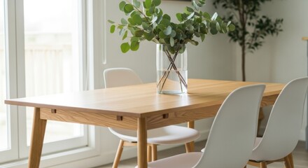 Light wood dining table with white chairs and eucalyptus in a glass vase wooden table