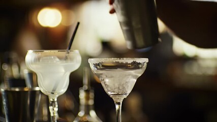 Bartender Skillfully Pours Margarita into a Salted Rimmed Glass from a Shaker in a Warmly Lit Bar with Bokeh Accents Perfect for Cocktail Advertising and Social Events