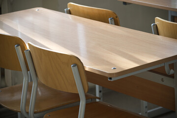 A wooden school desk and chair set in an empty classroom, waiting for students.