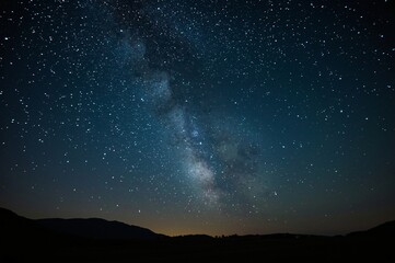 Milky Way galaxy over dark mountain range at night