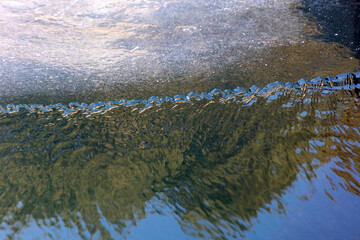 A landscape of ice and reflections on the riverbank