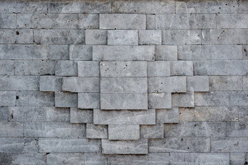 Symmetrical geometric pattern of a gray stone block wall. Modern architectural texture or abstract background with clean lines and a rough surface.
