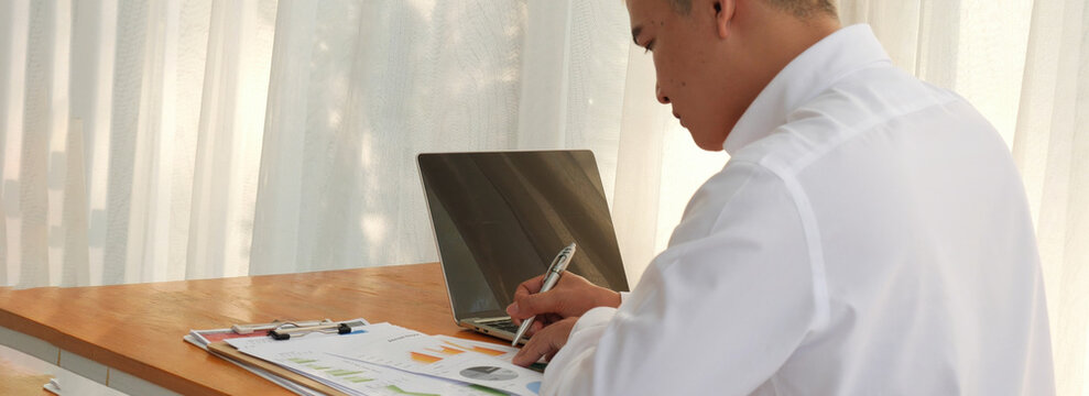 Banner Closeup businessman hands working use laptop finance business document reading report paperwork office desk. Banner Man hands type keyboard write on office note touch screen with copy space