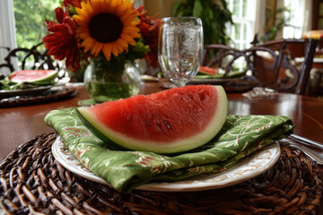 Watermelon slice on a vibrant green napkin set on a wooden dining table