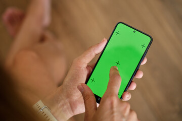 Hands holding smartphone and touching display with green screen and tracking markers. Person using mobile phone, close up