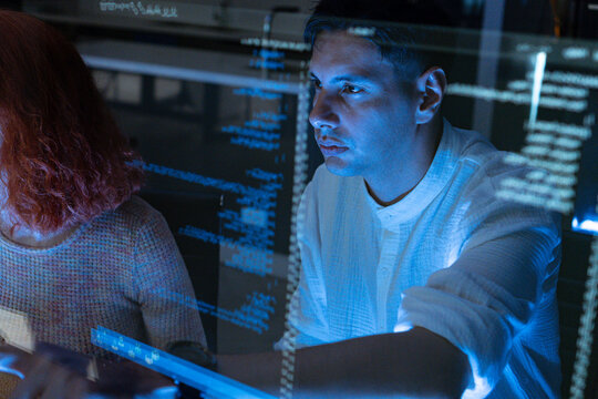 Professional IT Technical Support Specialist or Software Developer pointing and analyzing code in control room of computers.