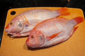 Red tilapia on a wooden cutting board ready for preparation and cooking