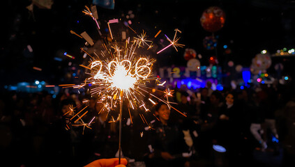 2026 new year with a festive atmosphere, colorful confetti and balloons scattered around, the sparkler held by a person with a big smile, capturing the magic and wonder of the moment,ai generative