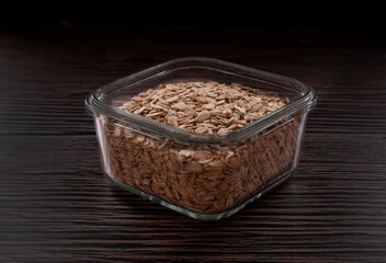 Square glass bowl with raw oats, on a dark background