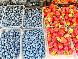 Vibrant display of fresh blueberries and strawberries at a local farmers market in summer