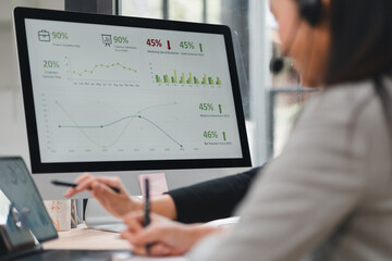 Office data analytics dashboard showing charts and performance metrics with two business professionals reviewing results in modern workspace, collaborative focus and analytical tone