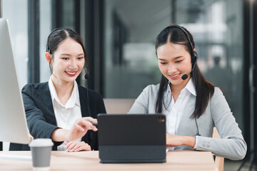 Fototapeta premium Young customer service agents smiling and collaborating on tablet while wearing headset in modern office, professional teamwork and supportive atmosphere