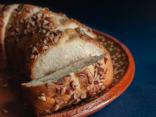 Slices of Mexican sweet pancake with walnut pieces on top on a clay plate. Macro photography.