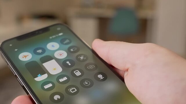 Close-up of a traveler's hand activating airplane mode on a modern smartphone, showcasing the simple process of enabling this essential travel feature