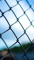 Fototapeta premium Close-up view of chain-link fence against a blurred sky