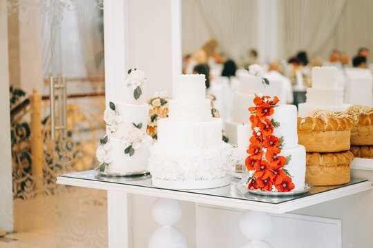 Elegant dessert table with beautiful wedding cakes surrounded by guests at a reception venue