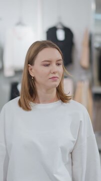 Woman walking through clothing store looking around at racks of stylish apparel, bright and organized setting features trendy fashion items