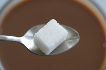 Adding sugar cube to hot beverage in a cozy setting