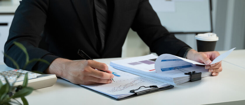 Close-up of man hand holding pen and smart phone working on table desk office. Workplace for student, writer with copy space. business working and learning education concept.