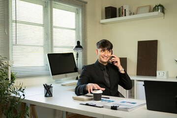 Naklejka premium businessman wearing classic suit talking on mobile phone sitting at table full of papers in office
